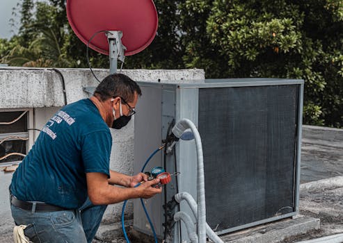 Technician repairing an air conditioner unit outdoors, wearing a facemask and using a manifold gauge.