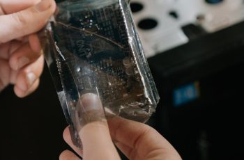 Close-up of hands holding a microchip in a computer repair setting.