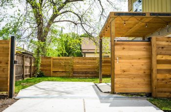 Sunlit wooden fence and patio gate in a peaceful backyard setting.